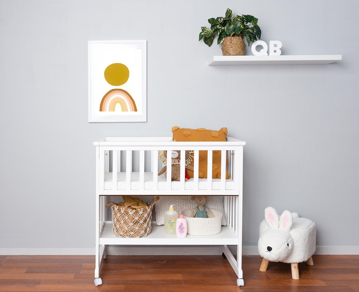White bedside bassinet with mattress and storage shelf